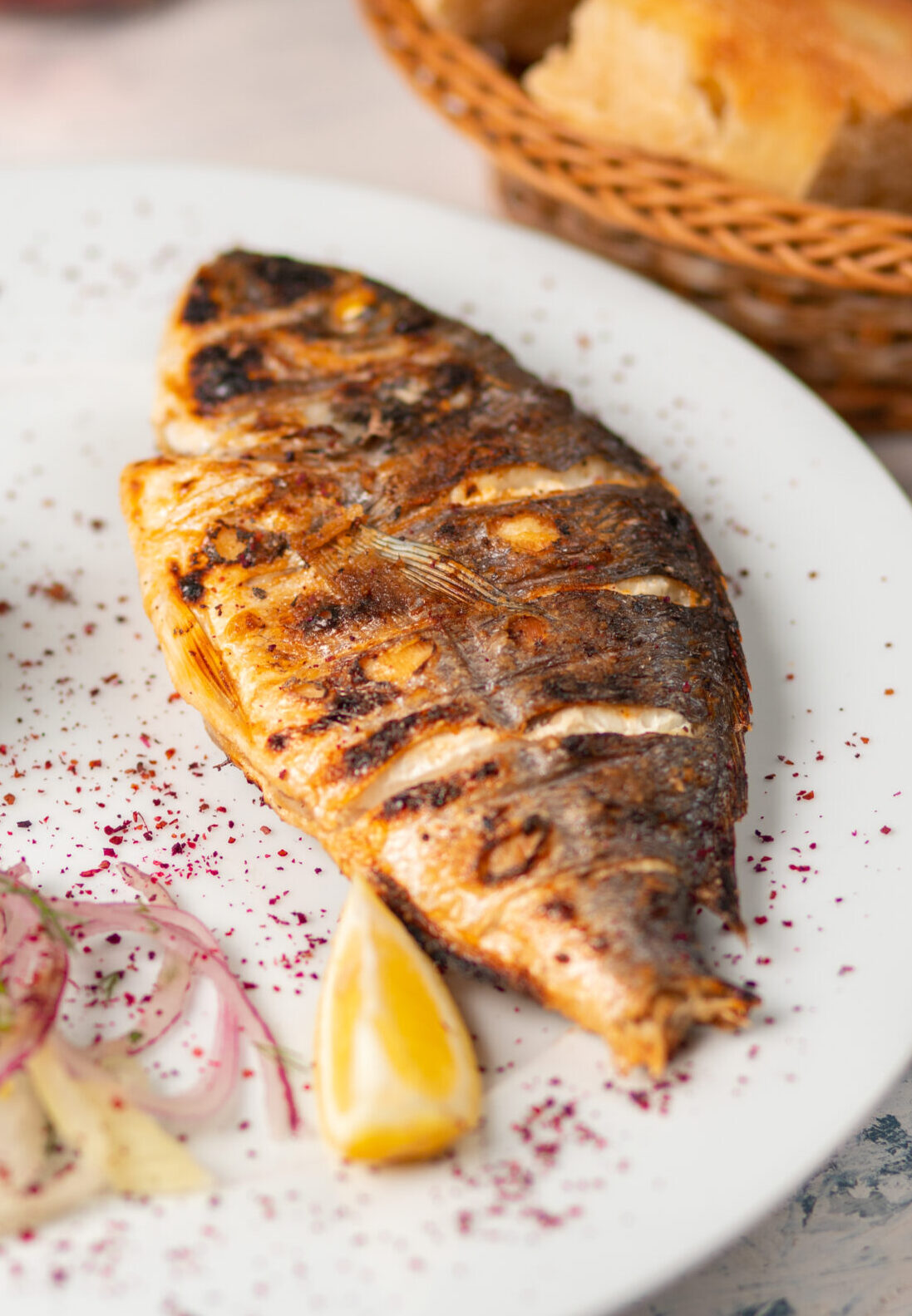 roasted-grilled-fish-served-with-herbs-lemon-onion-salad-dip-red-tomato-sauce